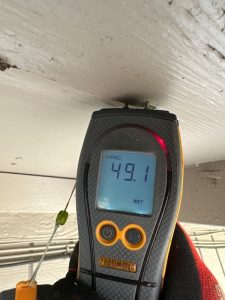 Moisture meter reading high level of moisture in wood soffit during a Zoom Home Inspection home inspection.